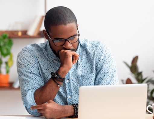homem negro em frente a um laptop com o semblante de preocupado