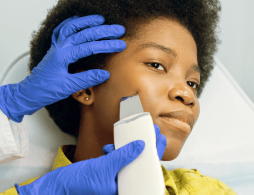 estaticista fazendo um procedimento no rosto de uma pessoa. Ela usa luvas de borracha azuis