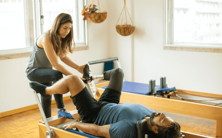 Mulher auxiliando homem com prótese a realizar um exercício físico