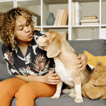 Mulher sentada em um sofá mandando beijo para um cachorro.