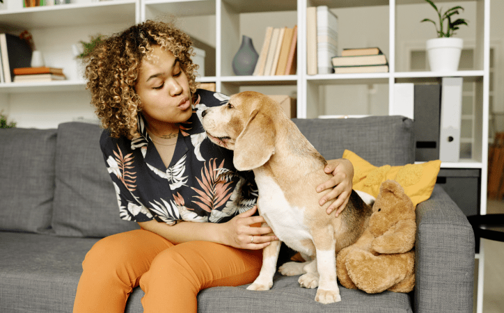 Mulher sentada em um sofá mandando beijo para um cachorro.