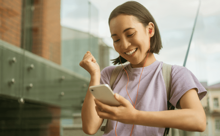 Mulher vestida de rosa ouvindo música de fone em um smartphone. 