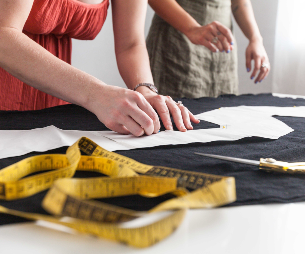 costureira tirando um molde de roupa com uma fita métrica amarela