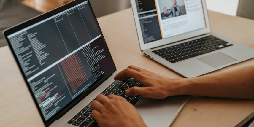 desenvolvedor criando códigos de programação com dois notebooks