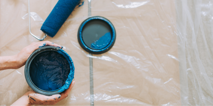 balde de tinta azul escura aberto e um rolo de pintura ao lado