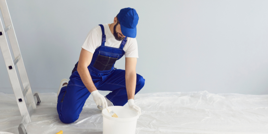 pintor vestindo um macacão azul preparando a tinta para pintar uma parede